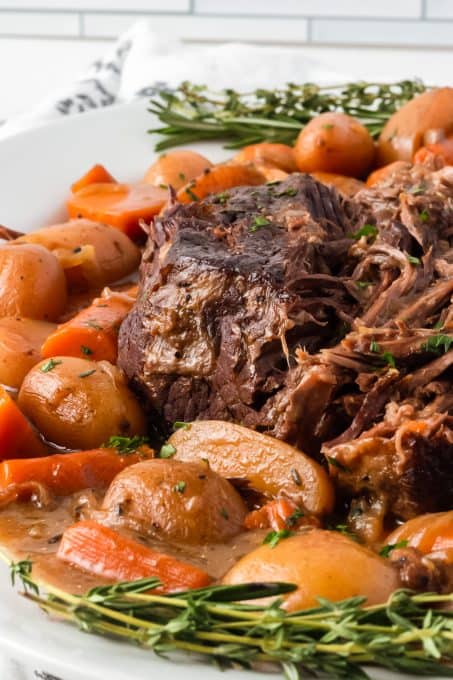 A roast, carrots and potatoes smothered in gravy and cooked in a slow cooker.