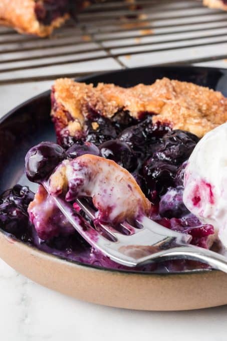 A bite of a peach galette with blueberries.