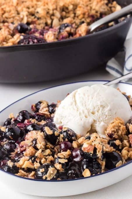 Easy Blueberry Crisp made in a cast iron skillet and topped with vanilla ice cream.