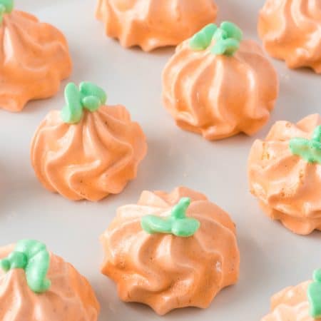 Green stems and leaves decorate pumpkins made of meringue.