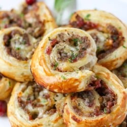 An appetizer with sausage, cranberry sauce, and brie