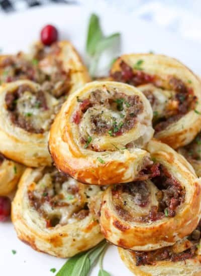 An appetizer with sausage, cranberry sauce, and brie