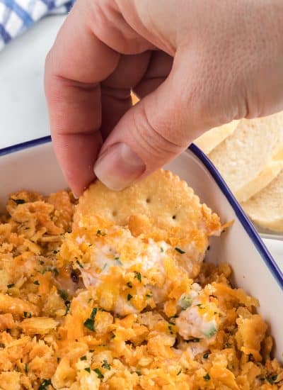 Scooping jalapeno cheese dip onto a cracker.