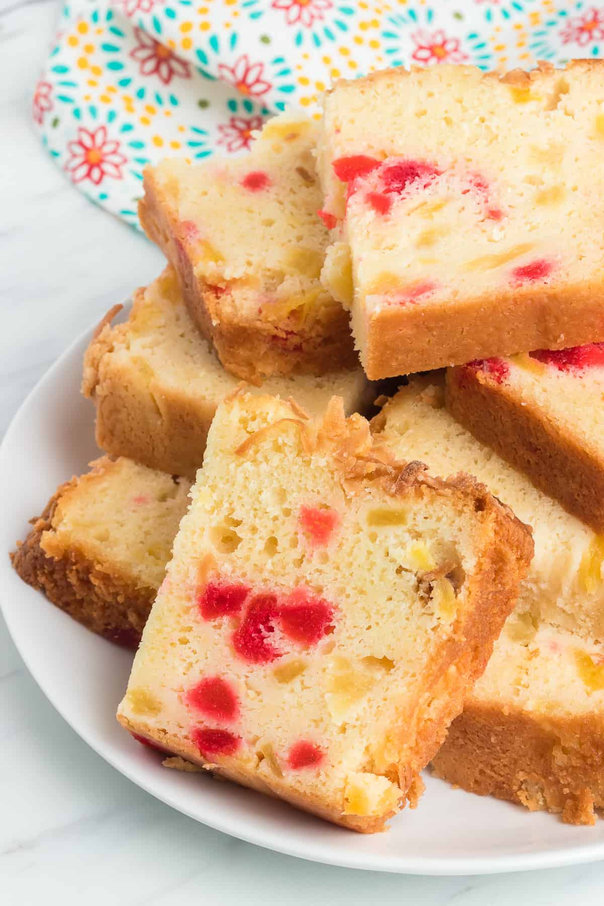 Slices of tropical quick bread with cherries, pineapple and coconut.