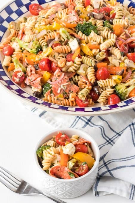 Bowls of pasta salad with olives, cheese, pepperoni, peppers tossed in an Italian dressing.
