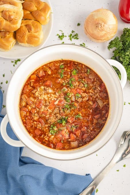 A pot of hearty soup with peppers, ground beef and onions.