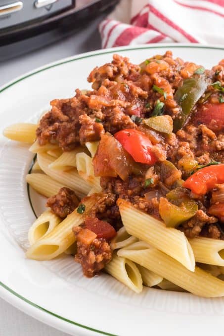 A meat sauce with peppers and onions on top of pasta.