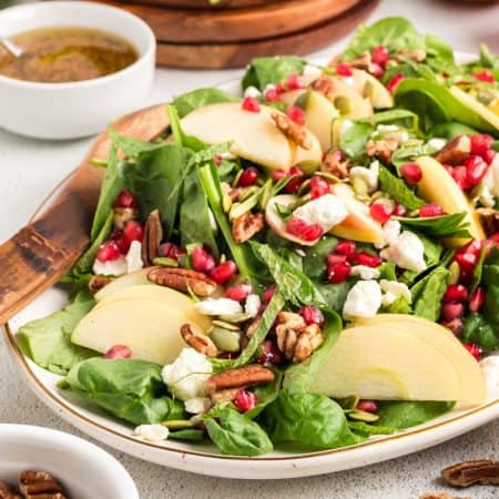 A spinach salad with apples, Feta, and pomegranate arils.