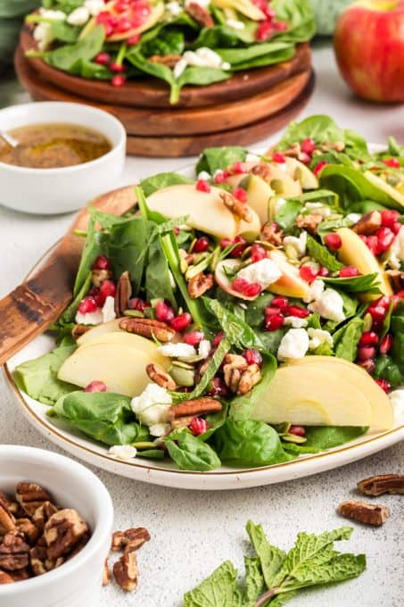 A spinach salad with apples, Feta, and pomegranate arils.