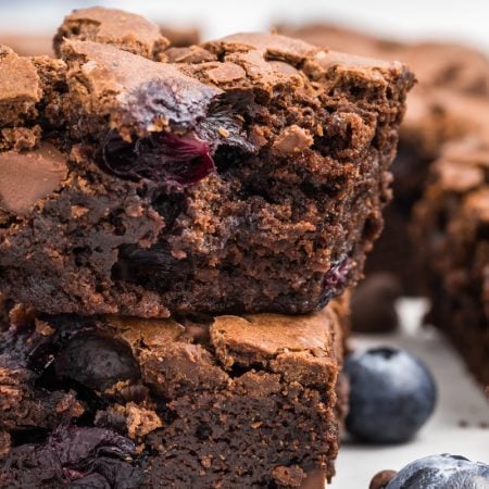 A bite taken out of a fudgy brownie filled with fresh blueberries.