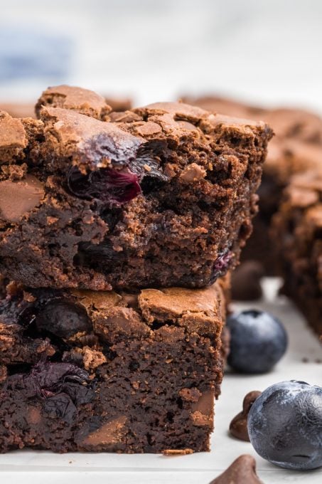 A bite taken out of a fudgy brownie filled with fresh blueberries.