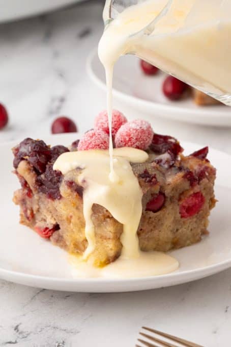 Pouring an orange Glaze over bread pudding with orange and cranberry.