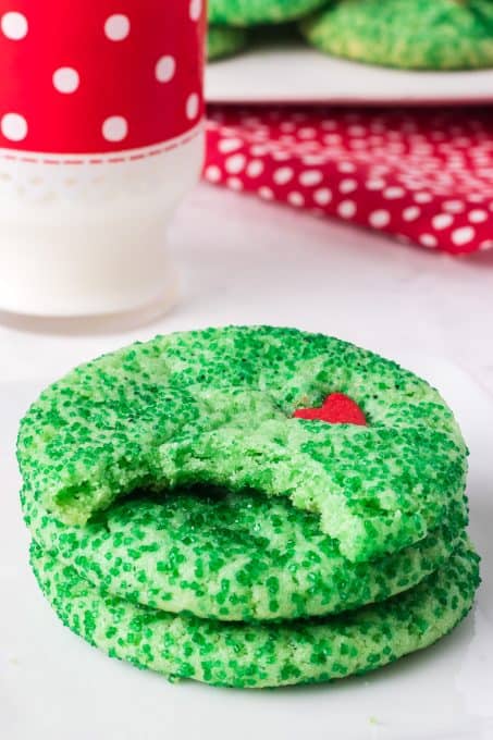 A bite out of a green sugar cookie with a red heart.