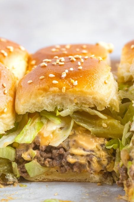 Ground beef sliders with cheese, lettuce, pickles, and sauce.