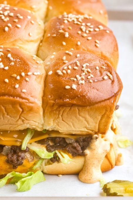 Special sauce, lettuce, cheese, pickles on a ground beef slider.